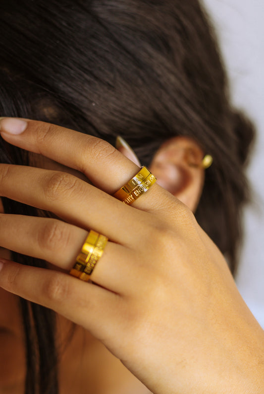 A person's hand wearing a gold rotating affirmation ring 